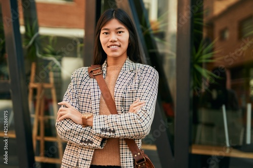 Young asian businesswoman with arms crossed smiling happy at the city.