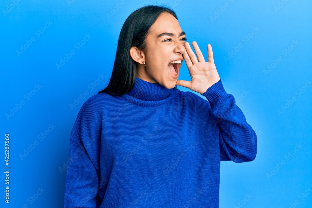 Young asian woman wearing casual winter sweater shouting and screaming loud to side with hand on mouth. communication concept. Young asian woman wearing casual winter sweater shouting and screaming loud to side with hand on mouth. communication concept.