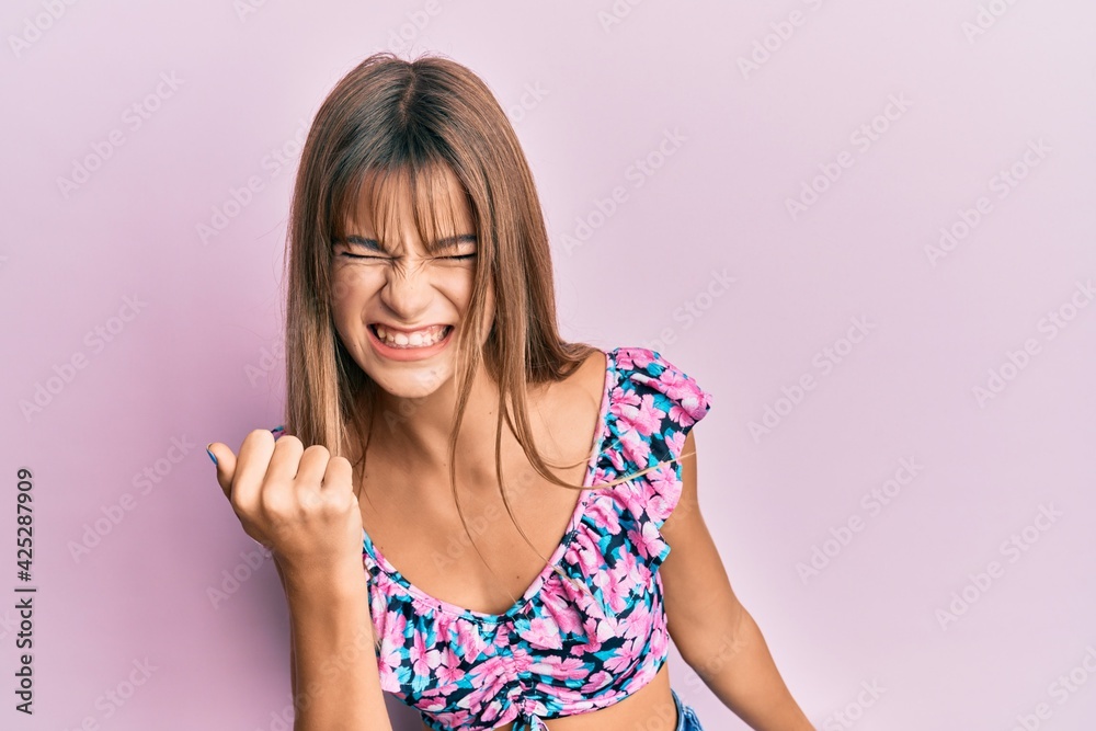 Teenager caucasian girl wearing casual clothes angry and mad raising fist frustrated and furious while shouting with anger. rage and aggressive concept. Teenager caucasian girl wearing casual clothes angry and mad raising fist frustrated and furious while shouting with anger. rage and aggressive concept.
