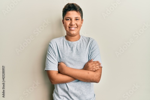 Teenager hispanic boy wearing casual grey t shirt happy face smiling with crossed arms looking at the camera. positive person.