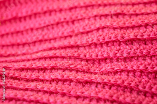 The structure of a knitted canvas of pink wool threads.