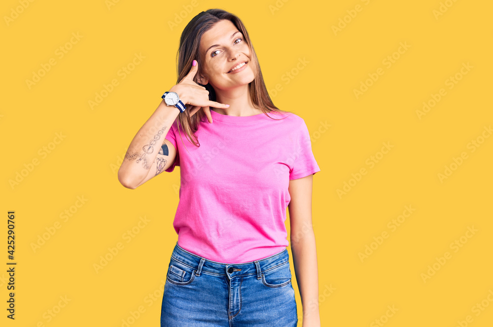 Beautiful caucasian woman wearing casual clothes smiling doing phone gesture with hand and fingers like talking on the telephone. communicating concepts. Beautiful caucasian woman wearing casual clothes smiling doing phone gesture with hand and fingers like talking on the telephone. communicating concepts.