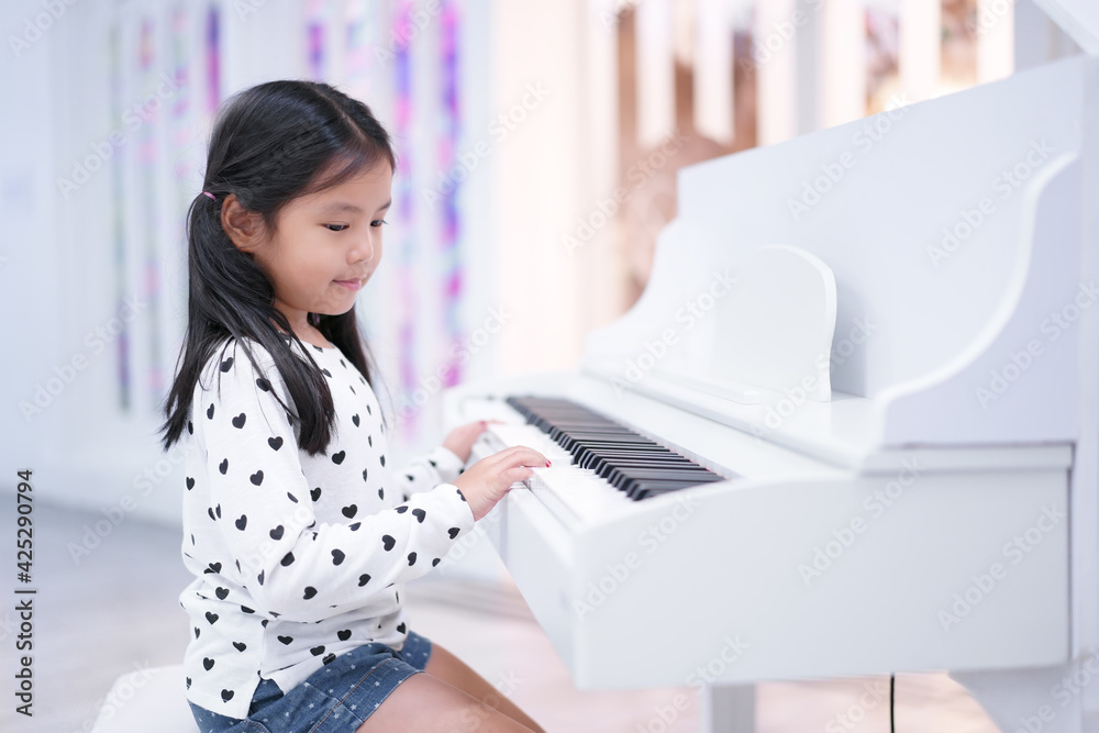 asian child cute or kid girl musician smile and happy playing white piano  or electone to song show on stage or people learn at music school for  artist education Stock Photo