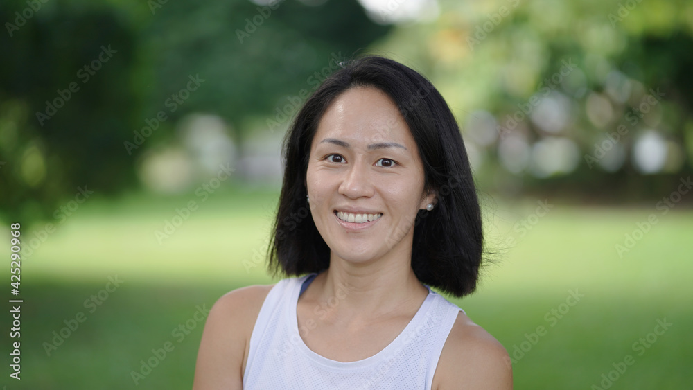 Asian chinese woman smiling sweetly outdoors garden active sporty Asian chinese woman smiling sweetly outdoors garden active sporty