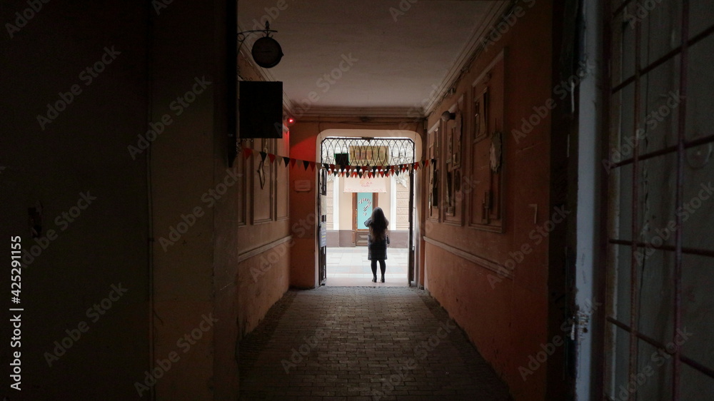 A girl stands under the arch of the entrance to the courtyard and takes pictures on the phone.