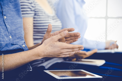 Business people clapping at meeting or conference, close-up of hands. Group of unknown businessmen and women in modern white office. Success teamwork, corporate coaching and applause concept