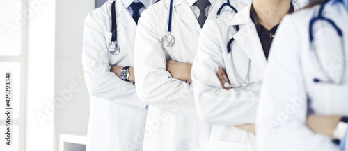 Group of modern doctors standing as a team with arms crossed in hospital office. Medical help, insurance in health care, best desease treatment and medicine concept