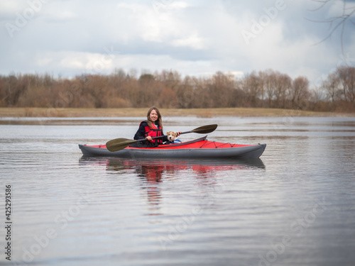 A beautiful girl and a Jack Russell Terrier puppy are traveling on a red kayak © WoodHunt