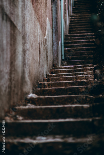 View of a long dark stone stair stretching up into the distance near a wall of an old building; shallow depth of field, selective focus on the steps in the middle