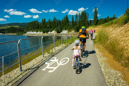 Family Cycling around Czorsztynskie lake near Niedzica village on sunny spring day, Pieniny Mountains, Poland
