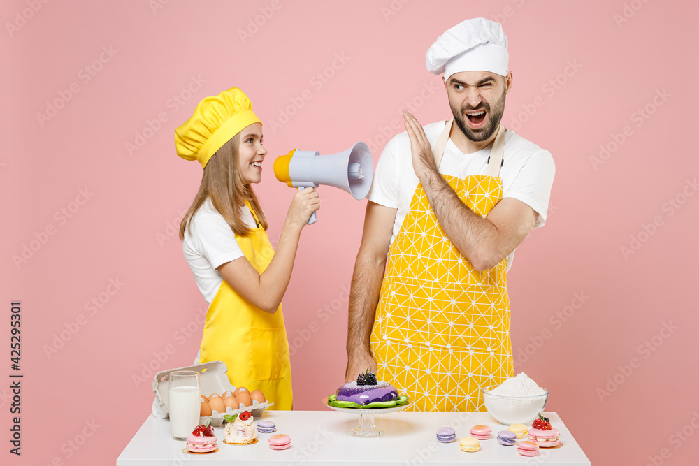 Teen fun girl dad father chef cook confectioner baker in yellow apron cap at table scream in megaphone fooling around play isolated on pink background Mousse cake food workshop master class process.