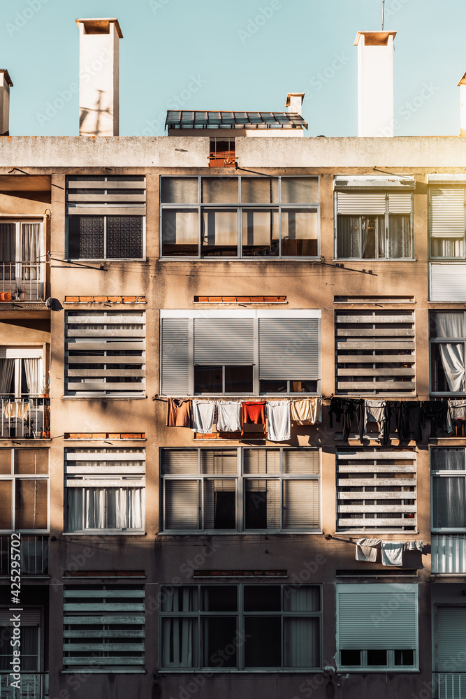 A vertical view of a typical facade of a residential house in Europe with balconies and multiple windows with hanging drying clothes, Lisbon, Portugal