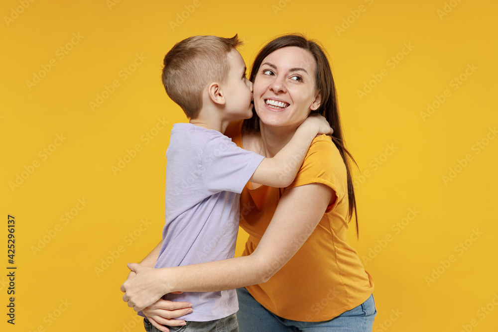 Woman have fun child baby boy 5-6-7 years old age in violet t-shirt whispering tells secret behind hand sharing news Mommy little kid son isolated on yellow background studio Mother's Day love family Woman have fun child baby boy 5-6-7 years old age in violet t-shirt whispering tells secret behind hand sharing news Mommy little kid son isolated on yellow background studio Mother's Day love family