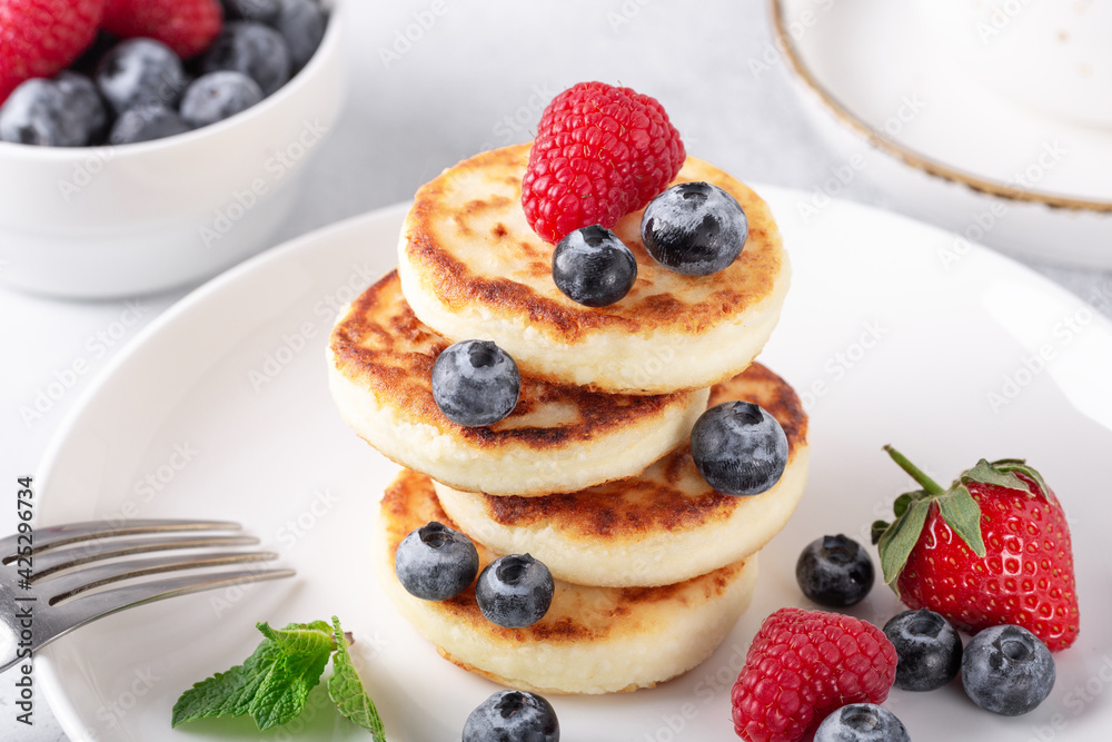 Cottage cheese pancakes with fresh berries, cup of coffee and on the table. Tasty breakfast food - Image
