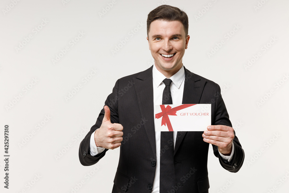 Young employee business corporate lawyer man in classic formal black grey suit shirt tie work in office holding gift voucher flyer mock up show thumb up gesture isolated on white background studio Young employee business corporate lawyer man in classic formal black grey suit shirt tie work in office holding gift voucher flyer mock up show thumb up gesture isolated on white background studio