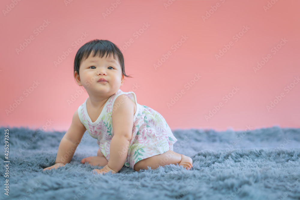 Asian baby smiling and sitting on carpet with pink color background. Cute 6 months baby sitting with copy space use as concept of valentine, love, learn, education, baby or kid department in hospital. Asian baby smiling and sitting on carpet with pink color background. Cute 6 months baby sitting with copy space use as concept of valentine, love, learn, education, baby or kid department in hospital.