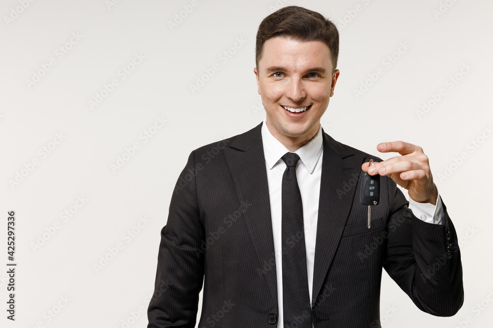 Young rich employee business corporate lawyer man 20s wearing classic formal black grey suit shirt tie work in office holding car keys fob keyless system isolated on white background studio portrait. Young rich employee business corporate lawyer man 20s wearing classic formal black grey suit shirt tie work in office holding car keys fob keyless system isolated on white background studio portrait.