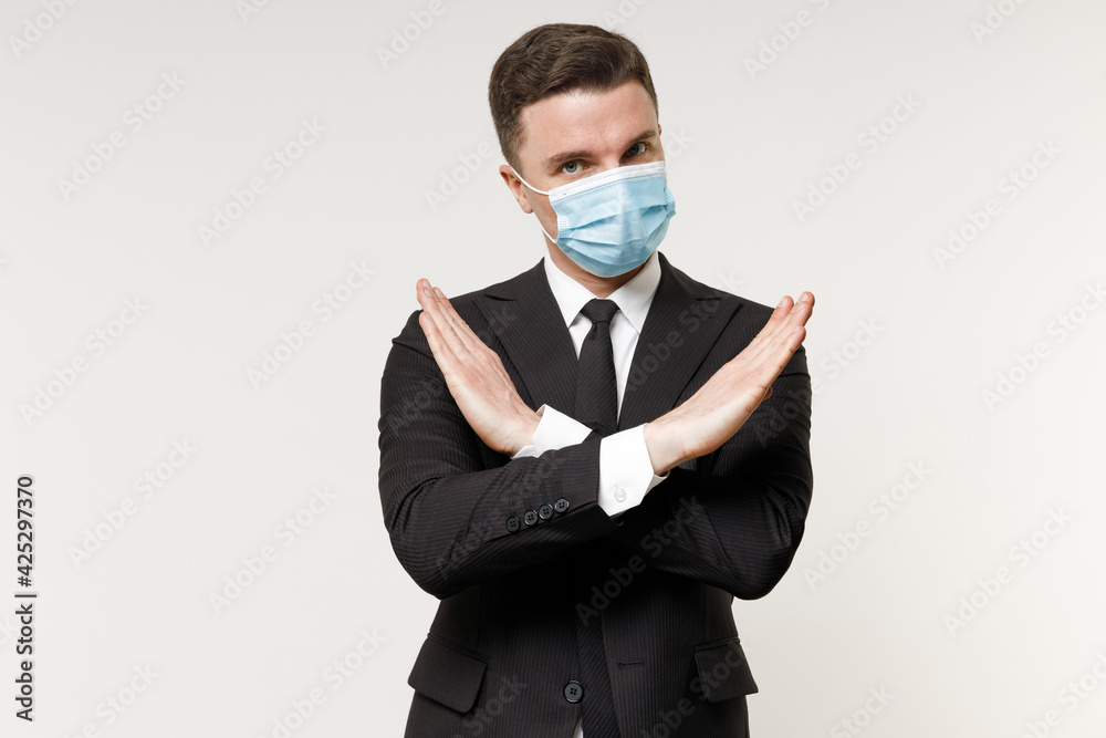 Young employee business corporate lawyer man 20s in classic black suit tie sterile face mask from coronavirus covid-19 pandemic quarantine work in office do stop gesture isolated on white background. Young employee business corporate lawyer man 20s in classic black suit tie sterile face mask from coronavirus covid-19 pandemic quarantine work in office do stop gesture isolated on white background.