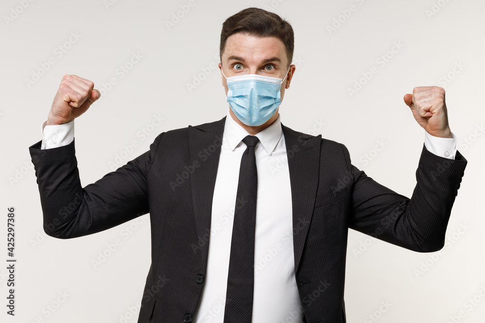 Young employee business corporate lawyer man in classic black suit tie sterile face mask from coronavirus covid-19 pandemic quarantine work in office do winner gesture isolated on white background Young employee business corporate lawyer man in classic black suit tie sterile face mask from coronavirus covid-19 pandemic quarantine work in office do winner gesture isolated on white background