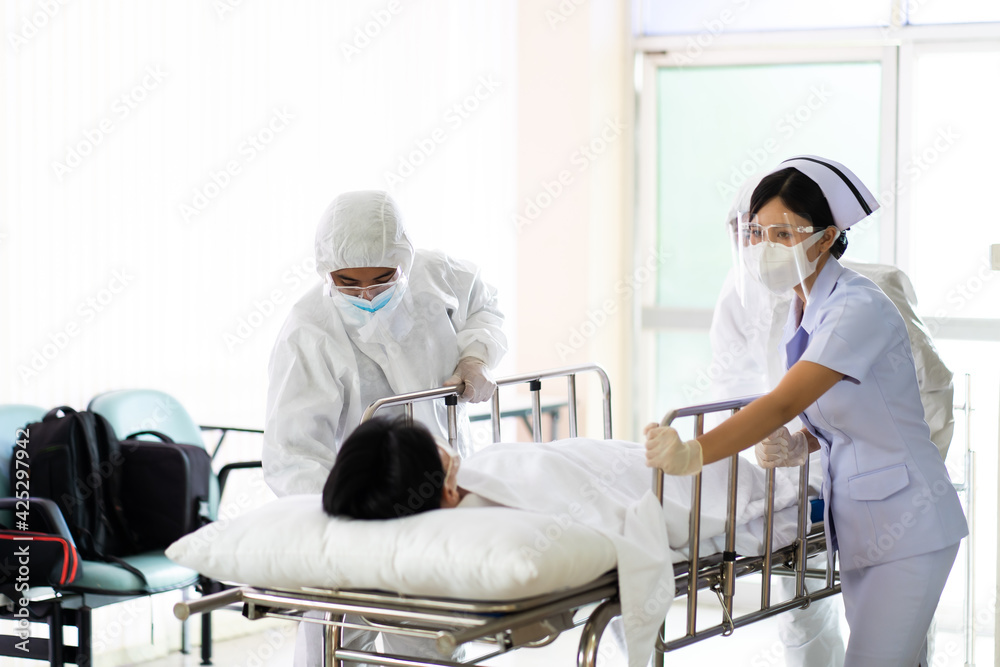 Group of medical technicians, wearing full protective equipment, were wheeling a patient lying on a hospital bed. Get tested for coronavirus