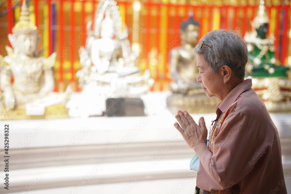 old asian senior woman traveler tourist praying at buddhist temple.