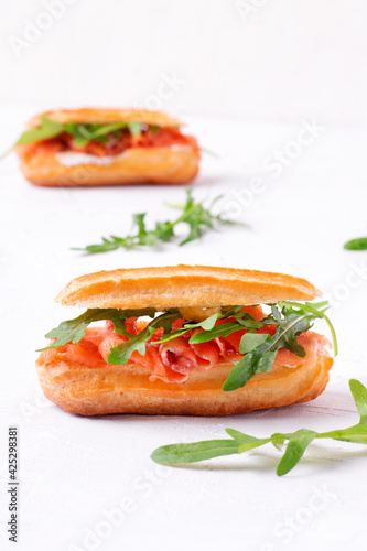 Eclair with salted trout, cream cheese and arugula on the white table photo