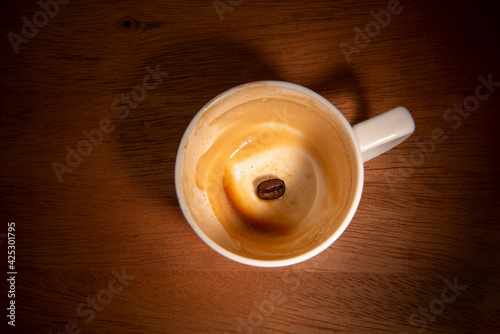 Vászonkép Empty coffee cup with precipitate and one coffee bean.