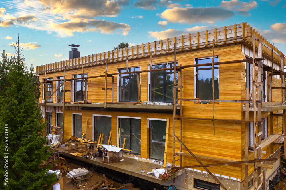 Facade cladding with wood. House under construction. Exterior decorationhouse with lumber. Two-story up to trimmed with wood. Facade of stone house is covered with boards. Аacade finishing services Facade cladding with wood. House under construction. Exterior decorationhouse with lumber. Two-story up to trimmed with wood. Facade of stone house is covered with boards. Аacade finishing services