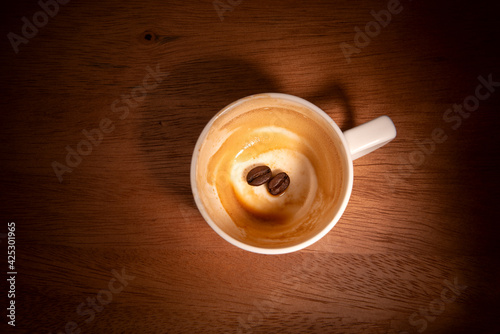 Empty coffee cup with precipitate and two coffee beans.