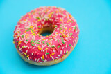 One pink donut on a blue background. Sweet snack.