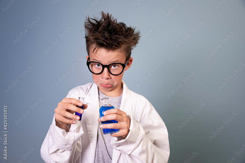 cool boy with wild hair and black glasses and white coat holds small bottle with blue liquid and looks like a mad scientist cool boy with wild hair and black glasses and white coat holds small bottle with blue liquid and looks like a mad scientist
