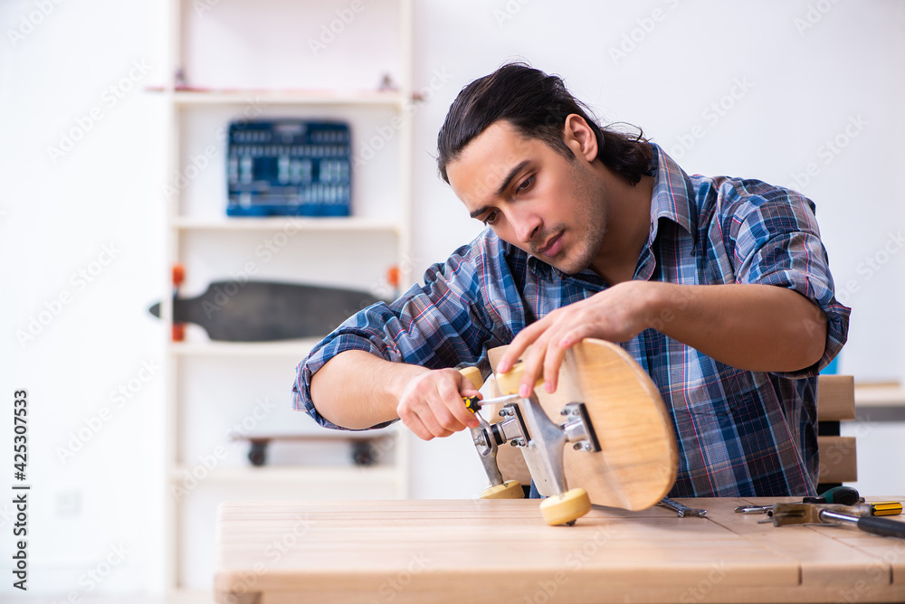 Young man repairing skateboard at workshop Young man repairing skateboard at workshop