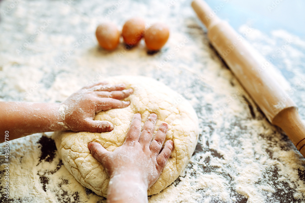 Children hands kneading dough on wooden table. Easter baking preparation. Cookies for Christmas. Little chef preparing cake in kitchen.