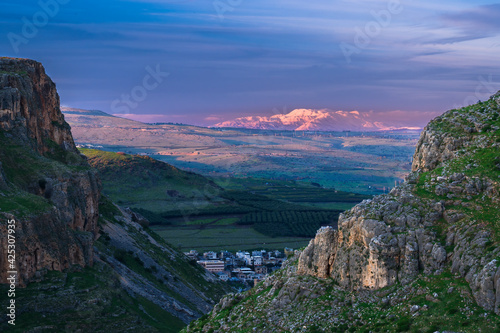 Beautiful view of Galilee from the cliff of Mount Arbel National Park and Nature Reserve, with the snow-capped Mt Hermon lit up by pink sunset light in the distance  Lower Galilee, Israel © John Theodor