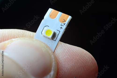 a person's fingers are holding a piece of 12 volt LED strip. close-up