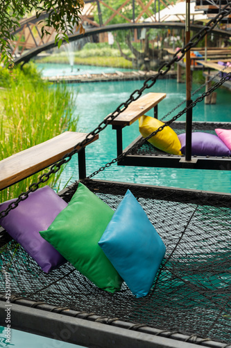 Comfortable colorful pillows lay on rope netting in garden for resting and relaxation.. photo