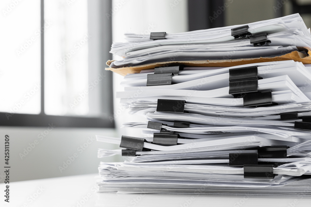 Piles of white papers work large piles of papers stacked together. On the desk in the office with black clip. Documents that are not finished. Business concept. Piles of white papers work large piles of papers stacked together. On the desk in the office with black clip. Documents that are not finished. Business concept.