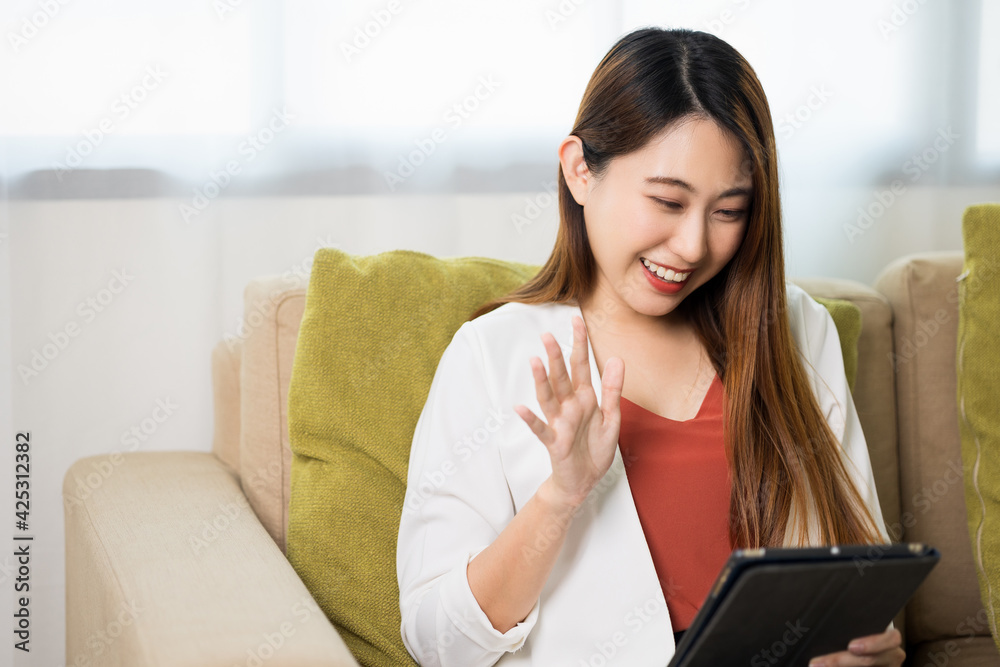 Young asian business woman sitting on sofa in living room at home working with tablet. Young asian business woman sitting on sofa in living room at home working with tablet.
