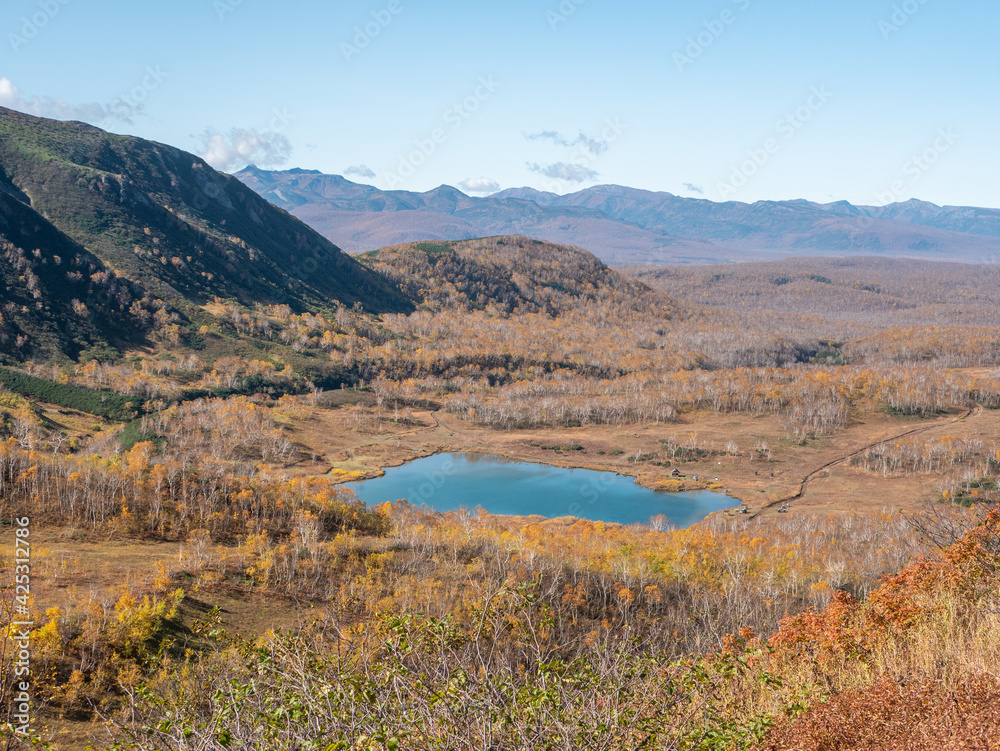 View of the lake and the Vachkazhets mountain range. Golden autumn adorns trees, mountains and hills. Kamchatka Peninsula, Russia.
