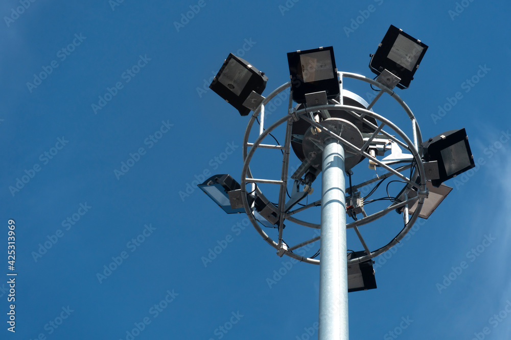 Under view of electric pole with Spotlight under the blue sky.