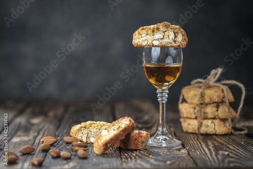 Biscotti cantuccini cookies, white dessert wine and almonds on a rustic background with copy space.