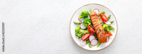 Salmon fish fillet grilled and vegetable salad with radish, tomato, green pepper, broccoli and asparagus on white background. Banner.