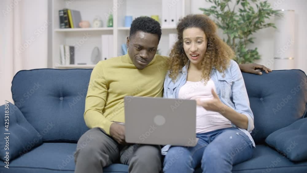 Glad expecting couple talking to family online sitting at home on sofa, internet Glad expecting couple talking to family online sitting at home on sofa, internet