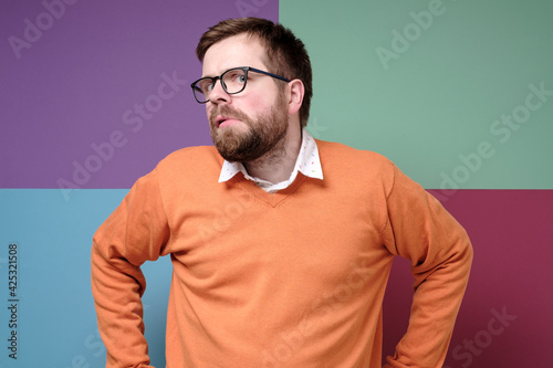 Strange Caucasian man looks suspiciously and incredulously to the side with a bizarre grimace. Colorful background. photo
