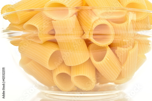 Light yellow uncooked durum wheat pasta in a glass dish, close-up.