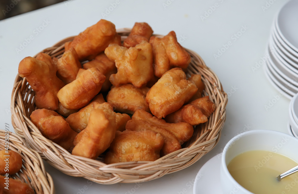Closeup of fresh golden brown deep fried crispy oriental doughnuts in bamboo basket on white table. Closeup of fresh golden brown deep fried crispy oriental doughnuts in bamboo basket on white table.