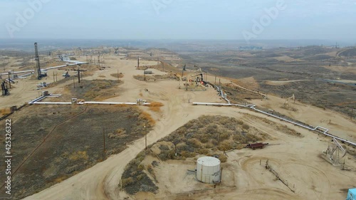 Aerial drone view over hydraulic well pumps, at a oil depot, cloudy day, in USA