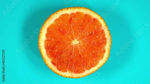 Blood orange slice rotating top view on light blue background.Macro food.Looped rotation.Healthy eating concept.Organic fresh harvest.healthy food,bio food.red fruit.
