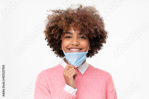 Bilde på lerret Portrait of smiling african american school girl taking off face mask after the end of pandemic