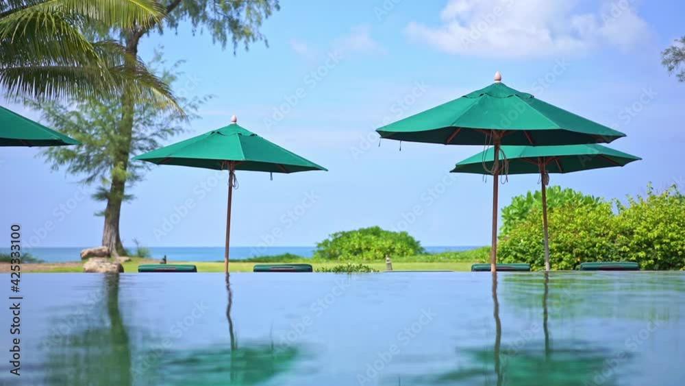 Sea view resort with infinity pool and green sun umbrellas. Low angle Sea view resort with infinity pool and green sun umbrellas. Low angle